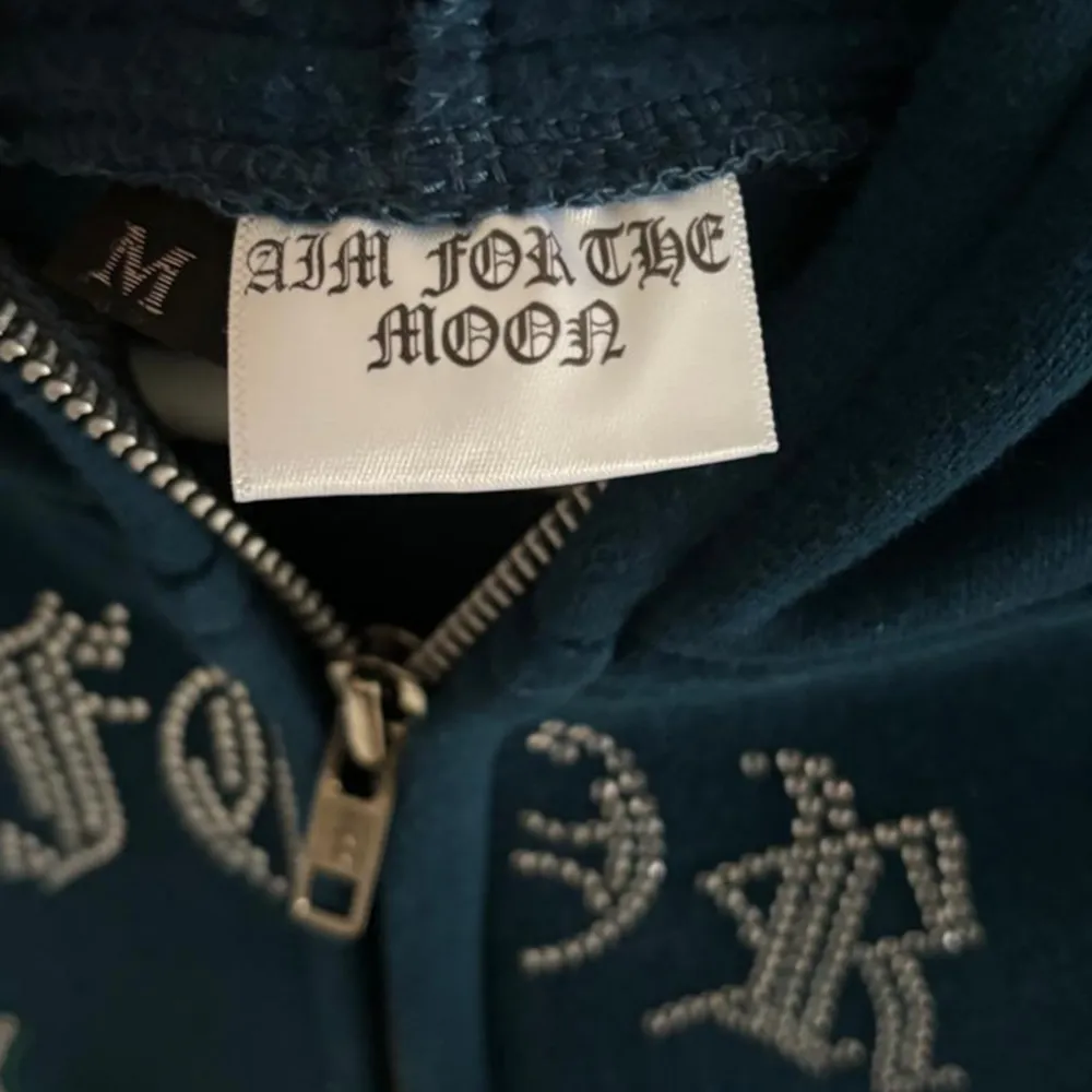 Säljer aim for the moon zip up i en grön-blå nyans. Köpt i början av sommar 2023, men har enbart används ett fåtal gånger. Tröjan har inga defekter och alla rhinestones är i bra skick. Vid övriga frågor är det enbart att kontakta oss. . Hupparit & Collegepaidat.