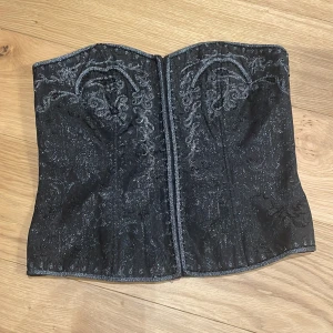 Korsett - Oanvänd korsett/partytopp strl 42. Svart med silvrig proderi och svarta pärlor