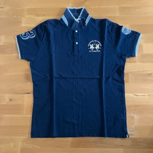 Mörklbå pikè - Mörkblå pikè med nice detaljer från märket La Martina. Stl 3XL men sitter som L/XL