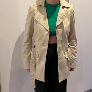 Kort trenchcoat - Kort beige trenchcoat från vila i storlek L, skulle mer säga att den passar till S då jag är en S/M.