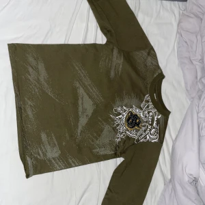 En grön dsben boys lång ärmad tröja med ett stort tryck i fram - Det är jätte bra skick på tröjan inga hål eller fläckar andvänd några gånger men tvättad!, måtten på tröjan är 65 cm lång och 45 cm bred 