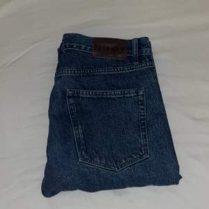Riktigt sköna & mörkblåa jeans från No Nationality. Modell Sonny 1816 Sttsight leg jeans. Nypris 1800kr. Använda men inga synliga tecken eller skador. Mått: Midja: 44cm Längd: 104 Innerbenlängd: 77cm Benvidd 21cm