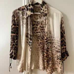 Authentic Roberto Cavalli 100% silk blouse originally purchased in Italy. Extremely rare modell with its faux leather straps on the sleeves and buttons in real copper.