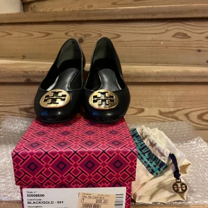 TORY BURCH Ballerina dam skor  - Fin begagnad ballerina från Tory Burch, populärt modell. Modellen kallas det: REVA BALLET, style nummer är 50008690 i Svart/Guld. Sälja med dustbag och i original skolådan. Gärna skicka ett mejl om önskar mer flera bilder av skorna. 