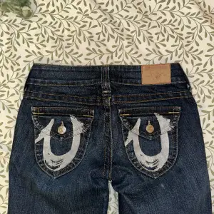 Jättefina lågmidjade raka True Religion jeans med väldigt snygga fickor bak, dem är från 2000-talet men mycket bra skick, dem är i storlek W26 och passar en XS till S beroende hur man vill de ska sitta, passar någon runt 160, diskuterbart pris