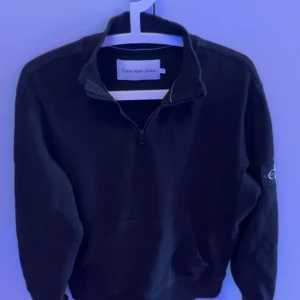 Calvin Klein halv zip - Svart Calvin Klein halv zip svart. Toppen skick som resten av våra kläder. Säljer för har ingen användning av den då jag har bytt still. Skriv vid intresse och frågor. Priset kan ändras