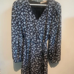 Blå klänning  - Säljer denna blåa klänningen med ljus blåa blommor. Klänningen är från är GLAMOROUS.