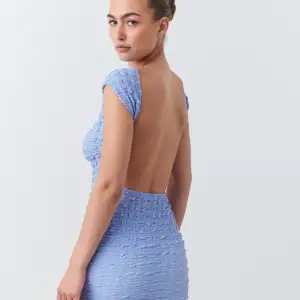 Jättefin ljusblå klänning i texturerat material, djup i ryggen.  Helt ny med prislappen kvar 
