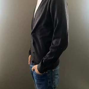 Merino Cardigan - Merino Cardigan från Bläck. Skicket är väldigt bra men de knappar som inte används är inte kvar på den. Modellen är 182cm och 70kg. Nypris:1800kr