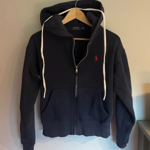 Polo Ralph Lauren Zip Hoodie - Säljer denna marinblåa Polo Ralph Lauren Zip Hoodie, i stl S men passar de som är 170. Alltså är den liten i storleken. Tröjan är mycket bra skick. Och har använts varsamt.  PRIS KAN DISKUTERAS VID SNABB AFFÄR. Kom privat för mer info/bilder