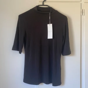 Svart topp - En jättefin helt ny ribbad topp med tre-kvartsarmar och en liten krage. Väldigt skönt material! Nypris ca 350kr. Fråga om du undrar något!🤍