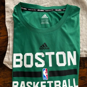 Långärmad Adidas NBA träningströja - långärmad grön träningströja med NBA-tryck ”Boston Basketball” framtill.  Lätt och luftigt climalite material perfekt för träningen. Storlek L men sitter som S-M.