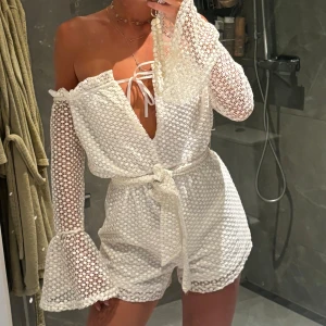 Spets Playsuit  - Helt ny med prislapp kvar. Vit Playsuit med band i midjan och trumpet ärm 🤍
