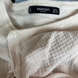 Beige kofta från Mango - En beige kofta från Mango Basics med knappar framtill. Koftan har ett diskret mönster och långa ärmar. färgen är ljusrosa och tröjan är jätte mjuk!💓