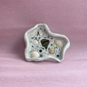 Hemmagjord smyckesskål - HEMMAGJORD!!   Smyckesskål gjord i lera som jag satt fast pärlor, snäckor och annat krimskrams och sedan lackat för att den ska hålla bra. Perfekt att ha smycken i eller ha som dekoration.