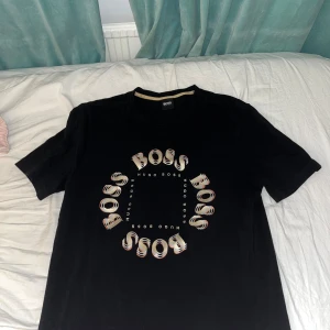 Hugo boss t-shirt - Snygg guldsvart Hugo boss t shirt som är i hyfsat bra skick, används inte då jag har vuxit ut den