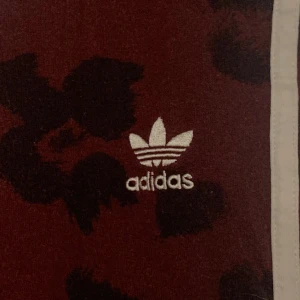 AdidasLeopard Leggings  - Fantastiska Adidas leggings i vin röd med svarta leopard fläckar eller blommor beroende på vem man är. Storleken kan ses som både S och M. De är dock små i storleken.