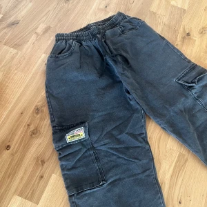 Mörk byxa - Fina mörkgrå, på gränsen till svarta, byxor. Väl använda men inga skavanker på dem. Resårband med snöre i midjan och fickor framtill samt på sidan av båda benen i lår-/knähöjd. Vida och lite korta i benen. Storlek S🥰