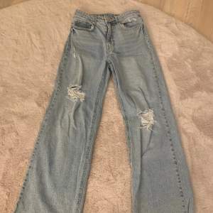 Säljer dessa ljusblå jeans med hål på knäna. Jeansen är högmidjade och de är från H&M. Använda ungefär 3 gånger. 