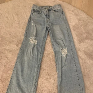 Jeans - Säljer dessa ljusblå jeans med hål på knäna. Jeansen är högmidjade och de är från H&M. Använda ungefär 3 gånger. 