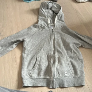 En dragkedje tröja  - Säljer En tröja som är förliten. Den har ett littet hål vid fickan men de märks inte så mycket.