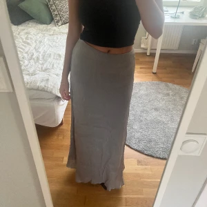 Silvrig maxikjol - Så så fin maxikjol, med så fint fall. Silvrig färg och går hela vägen ner på mig som är 170. Använd en gång så i nyskick.