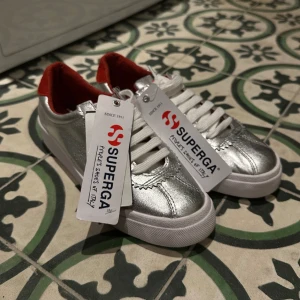 Helt nya skor från Superga - Helt nya silverskor från märket Superga. Skorna är i storlek 37, som man kan se på bild 3. Hör av dig om du vill se fler bilder eller veta något jag inte skrivit med. 