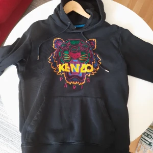 KENZO Hoodie - Klassisk Kenzo hoodie, med enligt mig den snyggaste färgkombinationen. Tröjan har en otroligt ingående och detaljerad brodyr av en tiger på bröstet. Bra skick, se bilder. Självklart äkta. Nypris 3300kr Storlek M