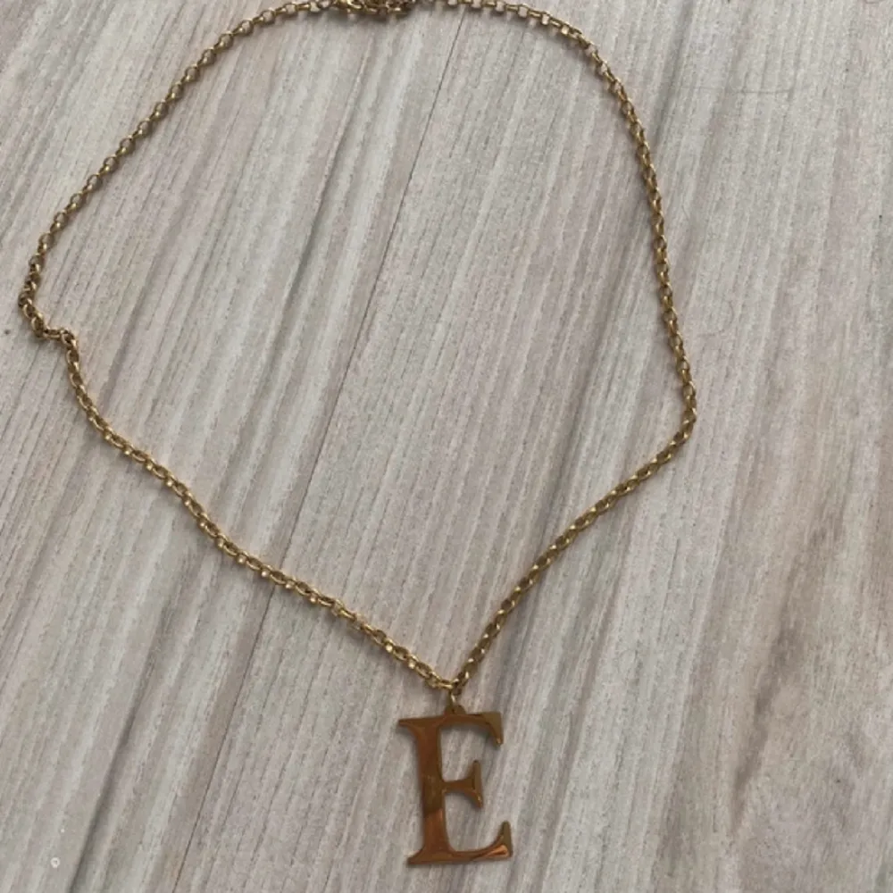 Säljer detta halsband med guldfärg med bokstaven E . Accessoarer.