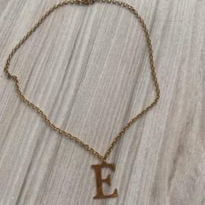 Säljer detta halsband med guldfärg med bokstaven E 