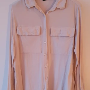 Beige skjorta medium  - Använd ett par ggr den är beige men ser rosa ut på någon bild. Strl Medium, bröstfickor liten krage. 100%viskos väldigt sval tunn samt len och behaglig att bära. Inga defekter. 