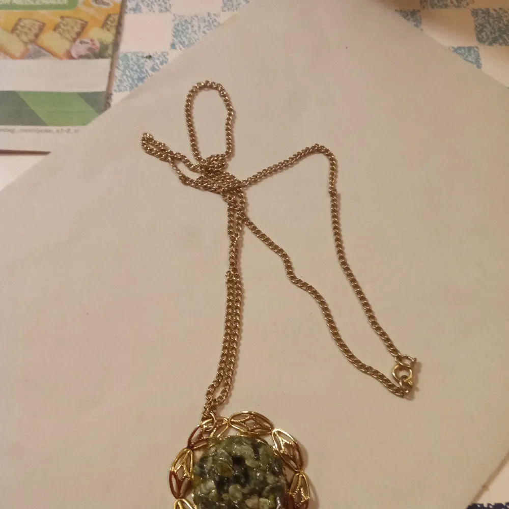 Vackert halsband med hänge av en blomma och gröna stenar i mitten guldfärgad ,inget slitage finnes .. Accessoarer.