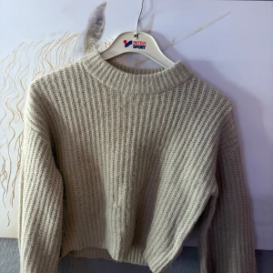 Beige stickad tröja från VILA - Supermysig beige stickad tröja från VILA i storlek S. Tröjan har en ribbad struktur, rund halsringning och långa ärmar. Perfekt för lager-på-lager och chill dagar. Enkel att matcha med jeans eller kjol för en avslappnad look.