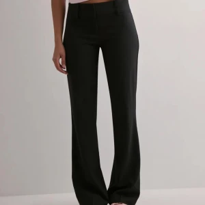 Svarta kostymbyxor med låg midja  - Svarta kostymbyxor från Nelly. De har låg midja och är något bootcut. De är använda men har inga defekter. 