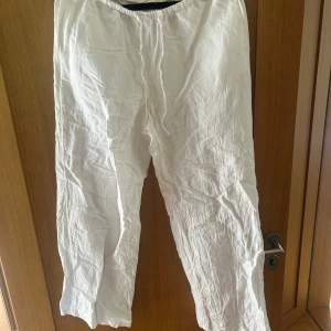 Vita linnebyxor från H&M, storlek S - Säljer ett par vita linnebyxor från H&M i storlek S. Byxorna har resår i midjan med snörning och två bakfickor. De är raka i modellen och tillverkade i en skön linnemix, perfekta för varma dagar.