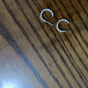 Glittriga silverörhängen i halvcirkel - Snygga örhängen i halvcirkel med glittriga detaljer som verkligen drar blickarna till sig. De är i silverfärg och har en cool, modern vibe som passar perfekt till din stil. Perfekt för dig som gillar att sticka ut med dina accessoarer.