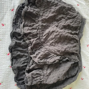 Grå volangkjol från H&M - Supersöt grå kortkjol från H&M med volangdetaljer och elastisk midja. Kjolen är gjord i mjuk bomull och har en skrynklig textur som ger en chill vibe. Perfekt att styla med en enkel topp eller hoodie.