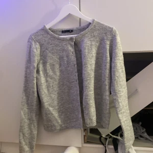 Grå kofta från 157, XS - Mysig grå kofta från 157 i storlek XS. Klassisk rund halsringning, knäppning framtill med matchande knappar och långärmad modell. Stickad i mjukt material som passar perfekt till lager-på-lager. Enkel och stilren design som funkar till allt.