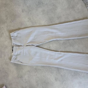 Beiga kostymbyxor från Bik Bok - Snygga beiga kostymbyxor från Bik Bok. Hällor för bälte/skärp och två fuskfickor bak. Väldigt sköna att ha på sig, säljs då de är för stora för mig, använt ett par gånger men inga fläckar eller skador på byxorna☺️