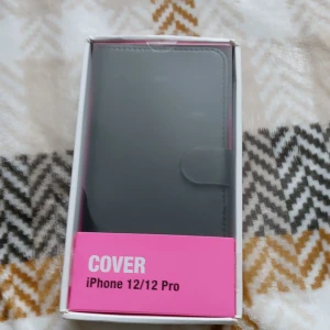 Svart plånboksväska till iPhone 12/12 Pro - Snygg svart plånboksväska för iPhone 12/12 Pro med magnetstängning. Stilren design i slätt material som skyddar mobilen.