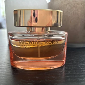 Michael Kors Wonderlust parfym - Michael Kors Wonderlust parfym i en lyxig glasflaska med mjuka former och en varm persikofärgad ton. Flaskan har en stor, rundad guldfärgad kork och guldtext på framsidan. Perfekt för dig som gillar eleganta och trendiga dofter. 30 ml, använd 2 ggr. Säljes då doften inte passar mig. Ingen kartong men fraktas säkert. Skickar nästkommande dag. 