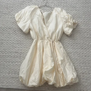 Champagnefärgad kort klänning H&M - Säljer en fluffig och champagnefärgad kort klänning från H&M med puffiga korta armar. Denna är m man jag har vanligtvis s och den passar! 