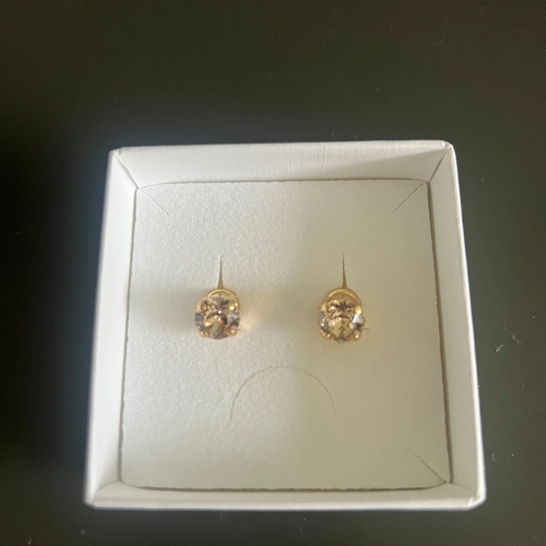 Guldiga örhängen med ljusa stenar