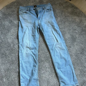 Ljusblå jeans från Lee W30 L30 - Säljer ett par ljusblå jeans från Lee i klassisk femficksmodell. Jeansen har raka ben, normal passform och är tillverkade i bomull. Snyggt Lee-märke på bakfickan och diskreta kontrastsömmar. Perfekta för en avslappnad stil. Bra skick och nytvättade. En liten gräsfläck på bakfickan. Skickas så fort som möjligt.