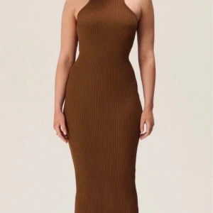 Brun ribbad långklänning - Adoore - Snygg brun ribbad långklänning med tight passform och ärmlös design. Klänningen har en hög hals och markerad midja som framhäver figuren. Perfekt för dig som gillar stilrena och trendiga plagg med enkel siluett. Stretchig !
