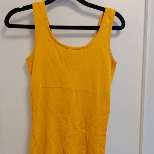 Gul ärmlös linnetopp - Snygg gul linnetopp med rund halsringning och ärmlös design. Perfekt för varma dagar och enkel att matcha med jeans eller shorts. Mjuk och skön bomullskänsla som gör den superbekväm att bära.
