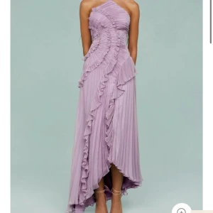 Ljuslila långklänning med volanger - Säljer en drömmig ljuslila långklänning med tunna axelband och snygga volangdetaljer framtill. Klänningen har plisserat tyg och en slits som ger extra flow. Perfekt för dig som vill sticka ut! Klänningen är inte använd och säljer den pga av att den satt lite tajt på mig :(