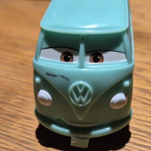 Plastbil ifrån filmen cars/bilar - Bilderna visar en leksaksbil som liknar en Volkswagen-buss med hippie-tema, dekorerad med ord som 'Peace', 'Love' och 'Groovy', samt färgglada blommor och regnbågar. Det är ingen bok på bilderna, utan en samlarleksak inspirerad av 60- och 70-talets fredsbudskap. Inköpt på Disney store I USA. 