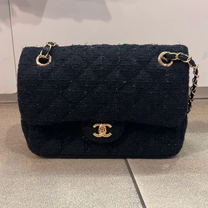 Svart axelväska från Coach i skinn - Stilren svart axelväska från Coach i strukturerat med guldfärgade detaljer och kedjerem. Väskan har jätte fint tyg 