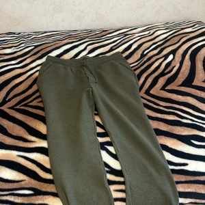 Olivgröna mjukisbyxor från lager 157 - Olivgröna mjukisbyxor från lager 157  i storlek XL men sitter som L på MIG. Byxorna har resår i midjan med snörning och är gjorda i ett mjukt, strukturerat tyg. Perfekta för chill dagar eller när du vill vara extra bekväm. Snygg och enkel design med fickor på sidorna. 